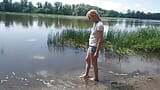 Alexa Kosmische transgirl zwemt in kleding in rivier in spijkerbroeken en wit t-shirt. Alexa kosmische wetlook-minnaar. snapshot 1