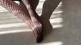 Girl in black fishnet pantyhose caresses her legs snapshot 9