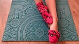 Gloria Gimson con calcetines rosas se acaricia los pies sobre una estera de yoga snapshot 13