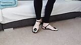 Le gambe sexy e il culo del travestito in leggings, i piedi nudi in splendidi sandali. snapshot 1