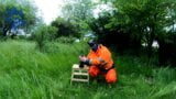 Riding dino toy in garden wearing hivis and rubber boots snapshot 2