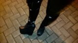 Ein Transvestit in Plateau-Schuhen mit hohem Keilabsatz und Latexleggings geht nachts durch die Straßen snapshot 5