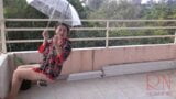 The lady is swinging on a hanging swing, hiding from the rain under an umbrella. snapshot 3