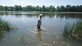 Alexa Kosmische transgirl zwemt in kleding in rivier in spijkerbroeken en wit t-shirt. Alexa kosmische wetlook-minnaar. snapshot 4