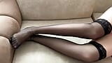 O fată în ciorapi negri își mângâie picioarele lungi snapshot 2
