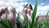 Des pieds de déesse dans de jolies chaussettes blanches avec un jean sur le champ d’herbe de printemps snapshot 4