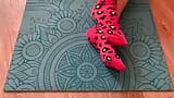 Gloria Gimson in pink socks caresses her feet on a yoga mat snapshot 7