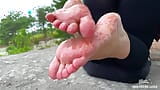 Mistress smears oil on her bare feet against the backdrop of the sea snapshot 2