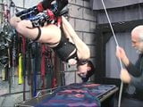 Brunette in bondage geer is hung from the ceiling by her hands and feet snapshot 4