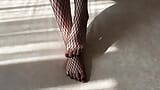 Una chica con medias de rejilla negras acaricia sus piernas snapshot 6