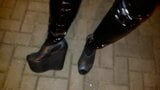 Ein Transvestit in Plateau-Schuhen mit hohem Keilabsatz und Latexleggings geht nachts durch die Straßen snapshot 1