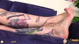 Barefoot blue eyed tattoed girl gives herself a foot massage snapshot 8