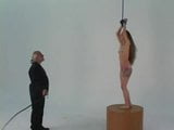 Longhaired bondage brunette with small tits stands on pedestal for whipping snapshot 13