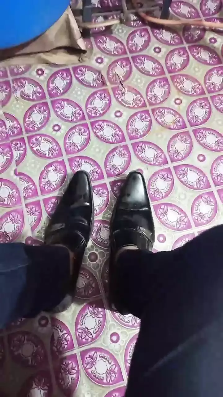 Bota de couro brilhando e pés pretos.