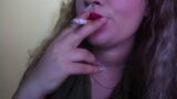 Une jolie femme peint ses lèvres en rouge et fume une cigarette snapshot 12